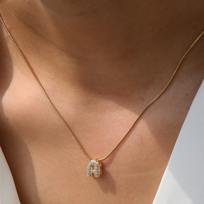 ✨ Collar inicial con letra inglesa, bañado en oro 18K y decorado con circonias incrustadas. Diseño puff/bubble llamativo, moderno y femenino, ideal para destacar tu estilo.