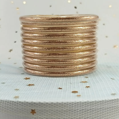 Set de 10 pulseras de silicona con glitter, en tonos cálidos dorados, ideales para complementar cualquier look femenino.
