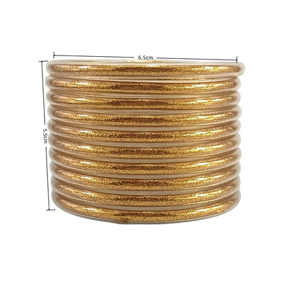 Set de 10 pulseras de silicona con glitter, en tonos cálidos dorados, ideales para complementar cualquier look femenino.