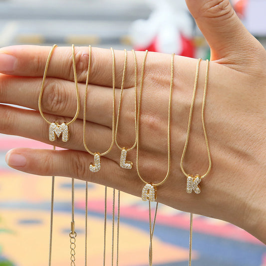 ✨ Collar inicial con letra inglesa, bañado en oro 18K y decorado con circonias incrustadas. Diseño puff/bubble llamativo, moderno y femenino, ideal para destacar tu estilo.