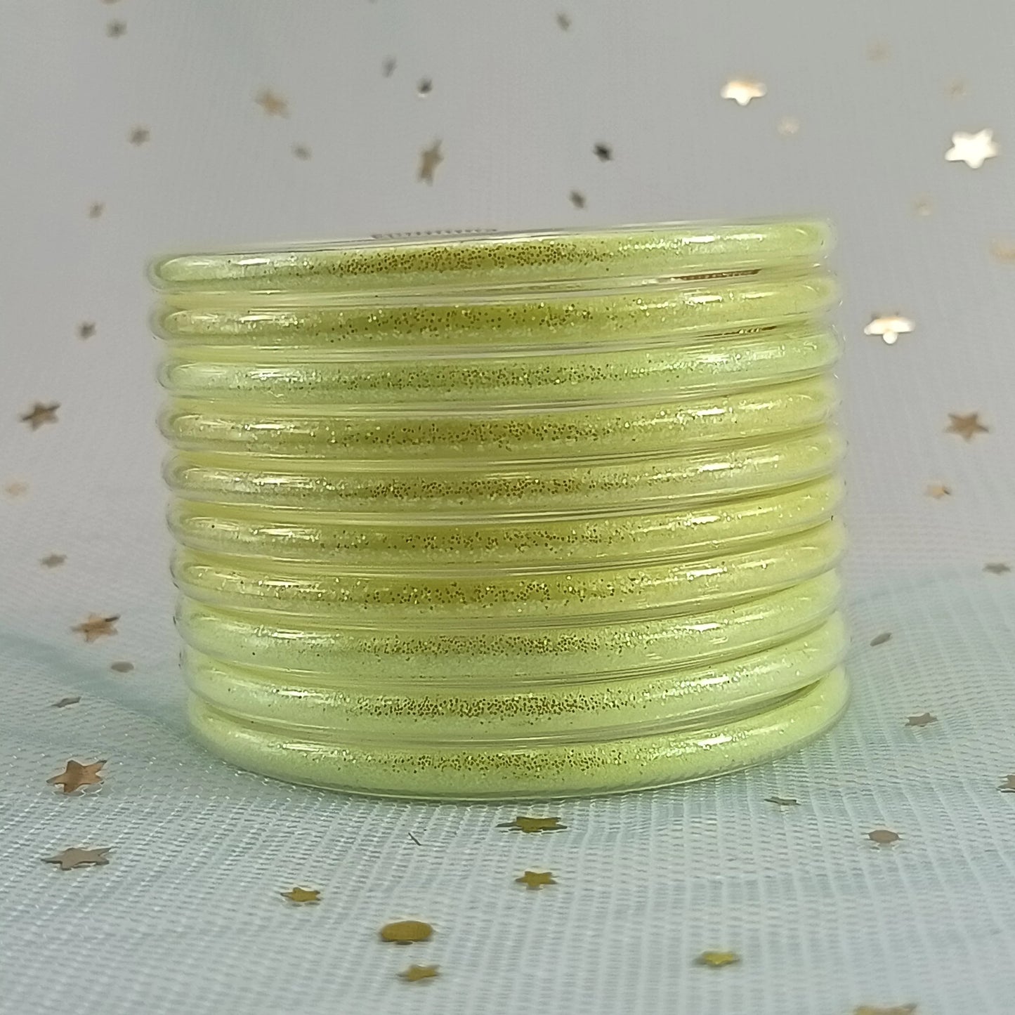 Set de 10 pulseras de silicona con glitter, en tonos cálidos dorados, ideales para complementar cualquier look femenino.